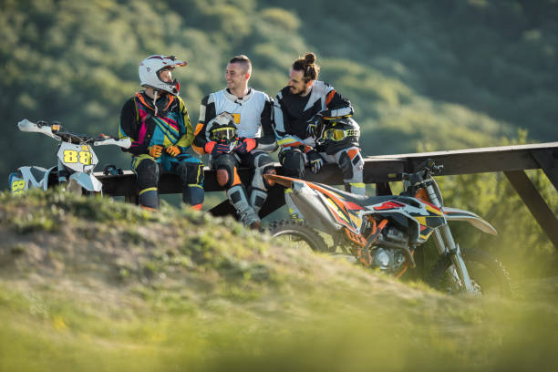 Three motorcyclists relaxing after race in nature and communicating.