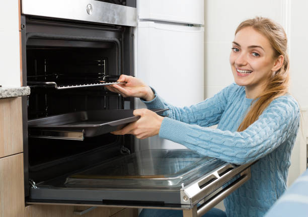 istock happy girl putting baking tray in kitchen oven 668185890