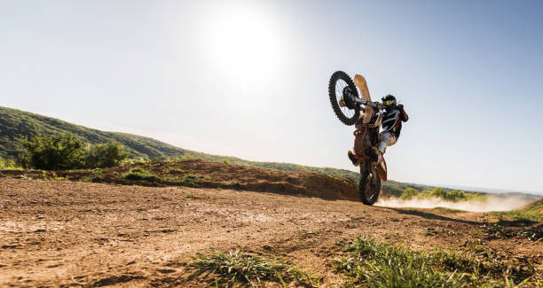istock Dirt biker racer balancing on back wheel on dusty road. 668188130