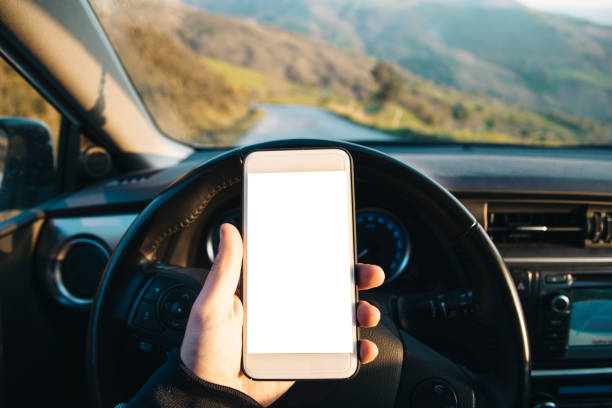 Holding mobile phone on car A hand holding a mobile phone while on a car tecnología inalámbrica stock pictures, royalty-free photos & images