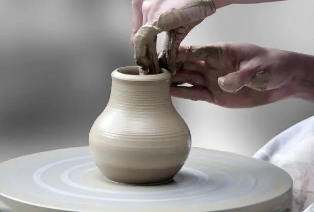 Woman's hands making ceramic cup on potter's wheel