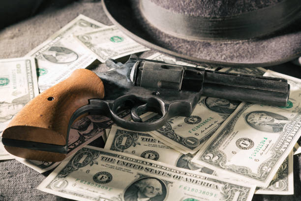 concepto de delito. pistola negra con sombrero y billetes de dólar. tonos de la imagen - gun currency crime mafia fotografías e imágenes de stock