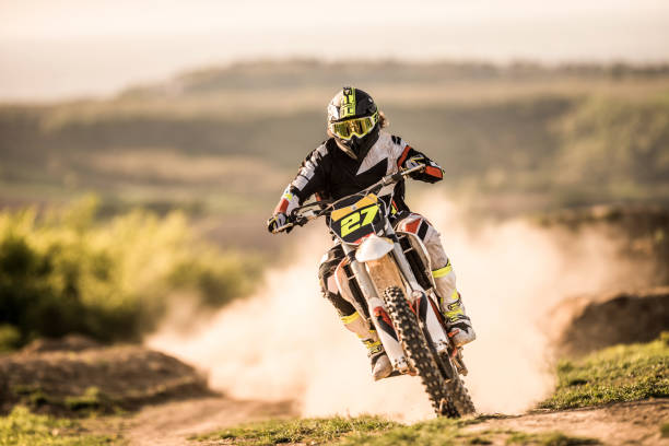 Man on dirt bike racing on dirt road in nature. Motocross rider driving fast while racing on dusty road. x games stock pictures, royalty-free photos & images