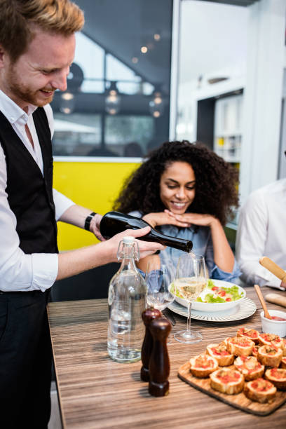 istock Happy man pouring wine to his guests 668193494