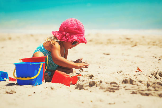 istock cute little girl play with sand on beach 668205054