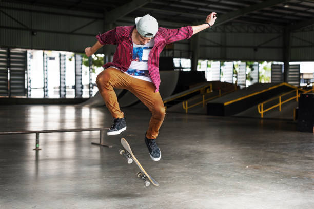 Silhouette of a young skater jumping with skateboard at a skate park at sunset. About 25 years old, Caucasian male.