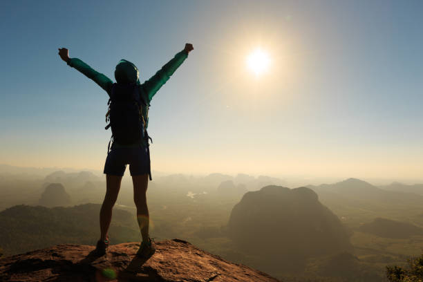 istock cheering successful woman hiker open arms on sunrise mountain top 668217880