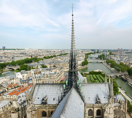 Top view of southeastern part of Paris from the tower of the Cathedral Notre-Dame de Paris with the roof and the spire of the cathedral on the foreground in the springtime