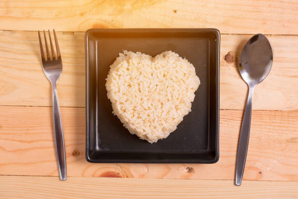 istock brown rice heart shape on black plate on wooden background 668224760