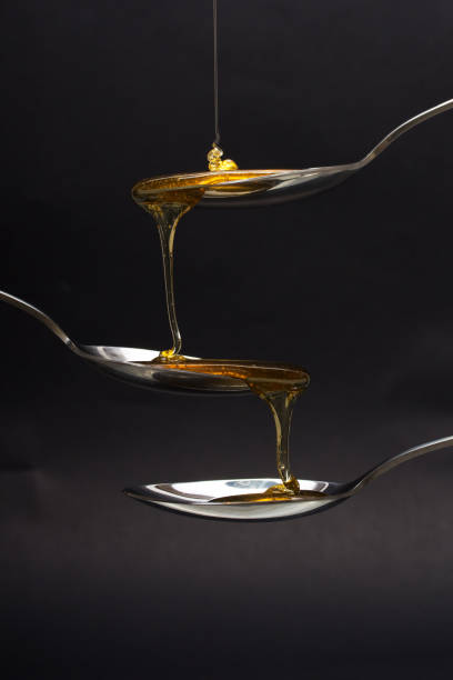 istock Honey pouring from spoon against a dark background 668226144