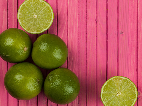 Fresh Ripe Juicy Limes Citrus Fruit Against a Pink Background