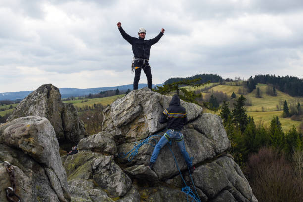 jeunes mâles grimpeurs au sommet de la roche - mountain climbing rock climbing adventure incentive photos et images de collection