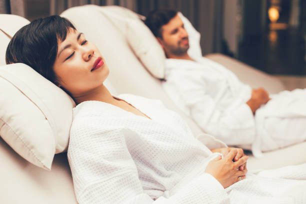 istock Man and woman dozing on deckchairs in spa salon 668242914