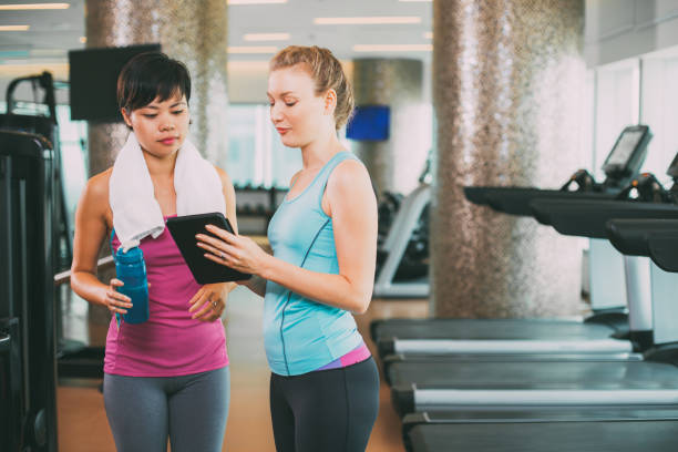 istock Two serious young women using tablet in gym 668243064
