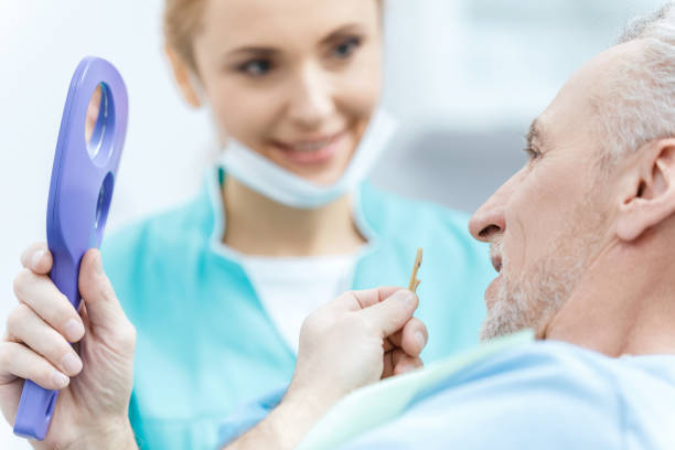 ミラーを保持する成熟した患者を見て笑顔のプロの歯科医 - dental light dental equipment hospital professional occupation ストックフォトと画像