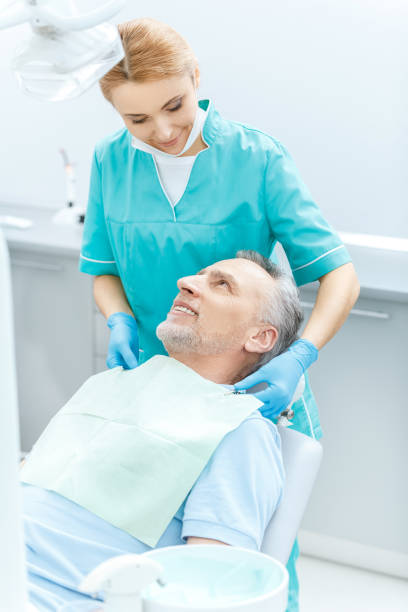 歯科医と成熟した患者が歯科医室でお互いを見ている笑顔 - dental light dental equipment hospital professional occupation ストックフォトと画像