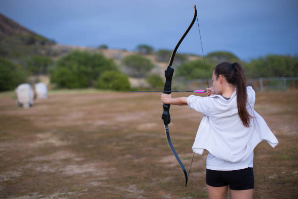 istock Athletic and athletic girl aiming a bow and arrow at an archery range. 668250014