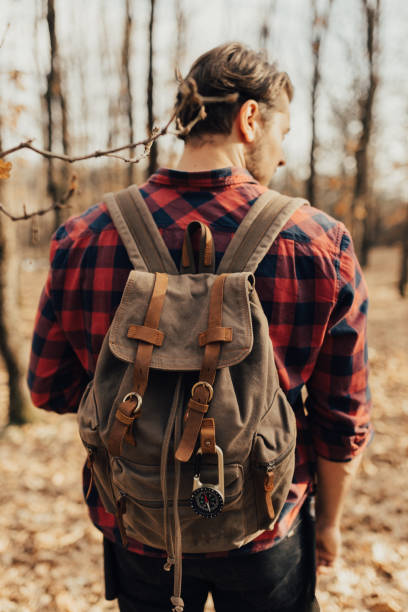 istock Man wearing backpack on his back in the forest 668254086