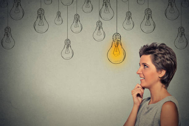 istock happy thinking woman looking up with bright light idea bulb above head 668271340