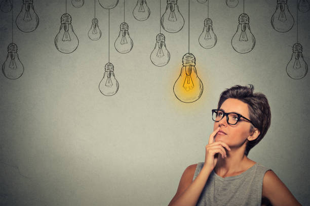 istock thinking woman in glasses looking up with light idea bulb above head 668272132