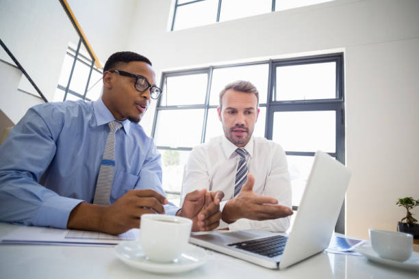 istock Businessmen looking at laptop and interacting in office 668278140