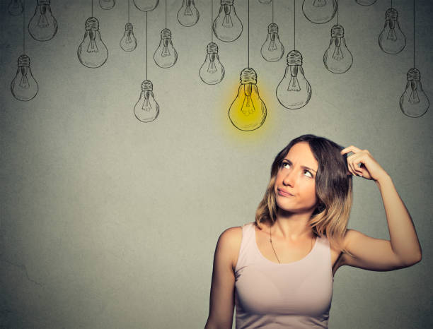 istock thinking woman looking up with light idea bulb above head 668285478