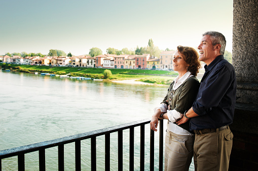 Portrait Of Happy Mature Couple Sightseeing And Capturing Photo From Camera, Ponte Coperto, Ticino River, Pavia, Italy