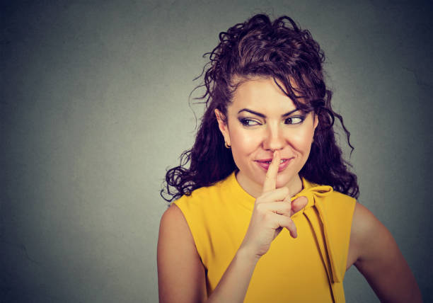 istock young woman making a quiet gesture looking to the side 668299602