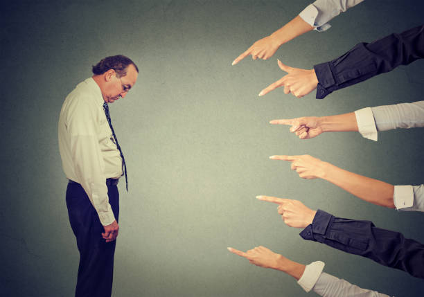 istock Side profile sad upset man looking down many fingers pointing at him 668329412