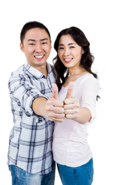istock Happy couple showing thumbs up against white background 668336110