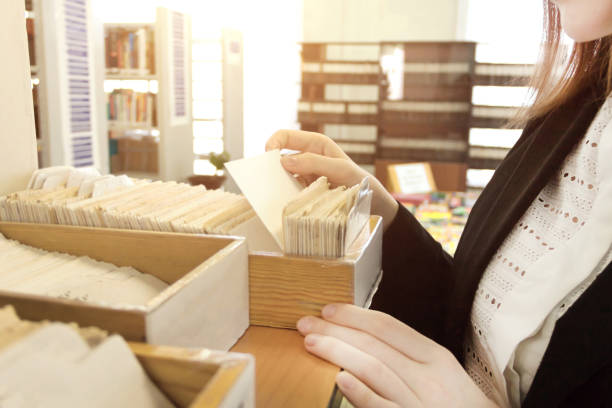 istock Librarian woman using old paper card catalog to find some informaton. 668340340
