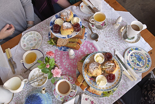 Afternoon Tea for four, cakes, scones, birds eye view, table filled with food and tea.
