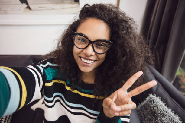 istock Curly haired girl taking selfie, peace sign 668344658