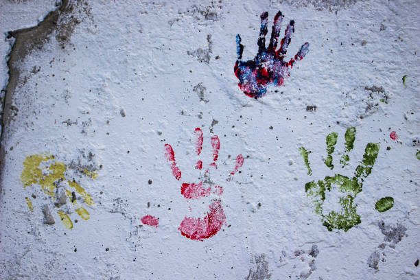 istock White dirty wall with colored hands print 668354226
