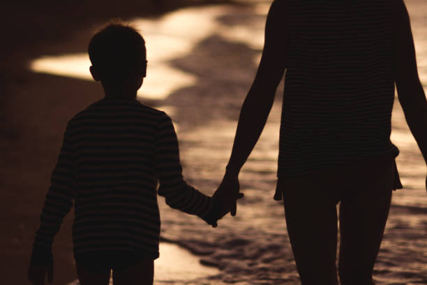 istock Mother and her son holding hands and walking 668361202