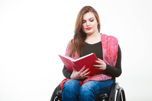 istock Young disabled woman in wheelchair with book. 668368190