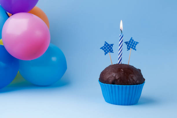 istock Cupcake with colorful birthday candle and balloons 668392354