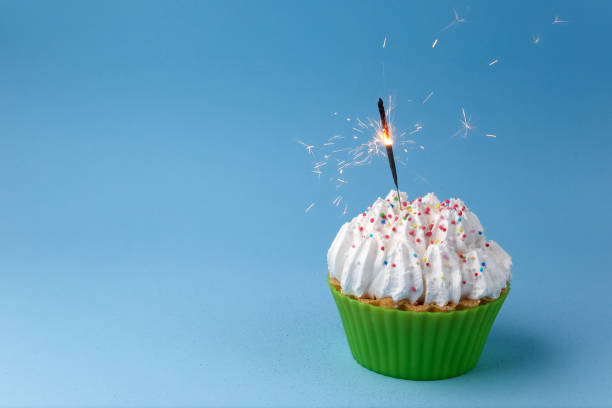 istock Cupcake with sparkler against a blue background 668393066