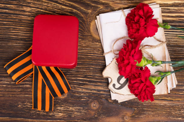 istock George's ribbon on the table with three carnations and letters 668396014