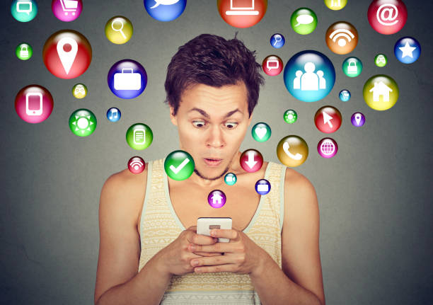 istock Shocked handsome man using texting on smartphone application icons flying out of cellphone screen 668409304
