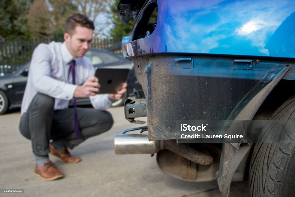 Junge männliche Geschäftsmann / Autoverkäufer checks Schrottauto mit Tablette vor Verkauf - Lizenzfrei Vereinigtes Königreich Stock-Foto