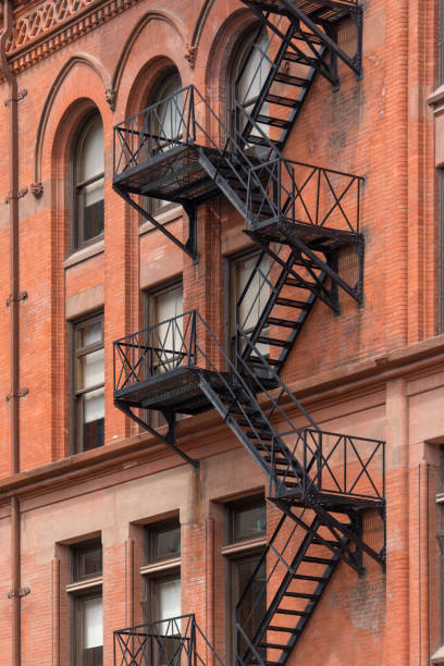 Fire escape Full frame facade of an old brownstone apartment building with iron fire escape stairs in  a historic downtown district. flatiron building toronto stock pictures, royalty-free photos & images