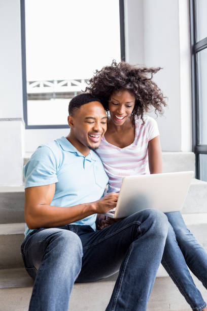 istock Happy couple sitting on steps and using laptop 668425562