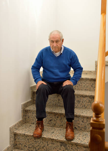 istock pensive senior man sitting on the stairs 668430228