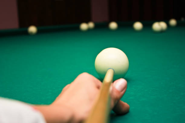 istock Close up man hand with cue and white ball on the billiard table 668430534