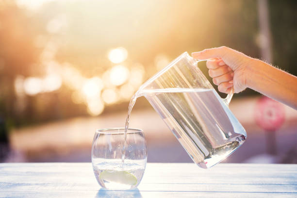 pouring water from pitcher into glass - going into imagens e fotografias de stock