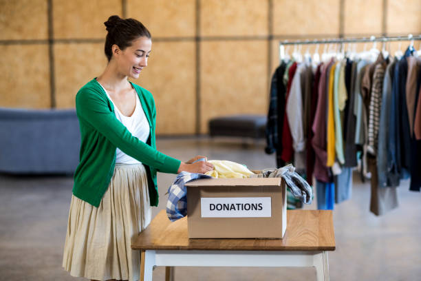 istock Young woman sorting clothes from donation box 668477716