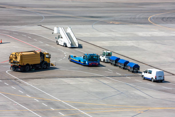 istock Airfield universal cleaning machine, pushback tug, passenger boarding steps vehicle, tractor with baggage carts and minivan at the airport apron 668503756