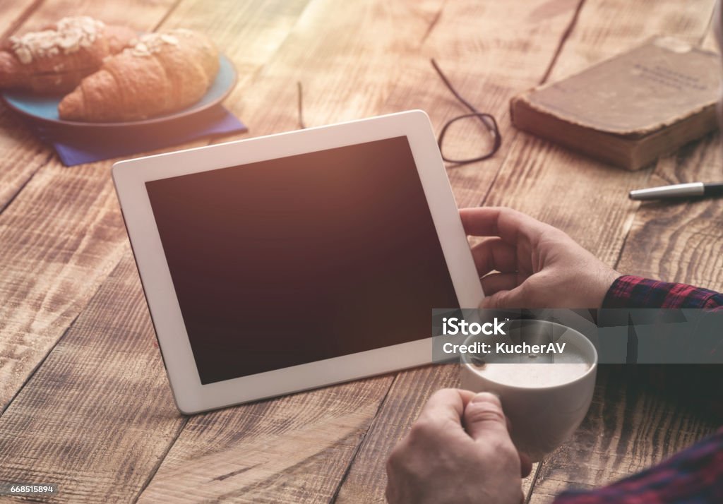 Mâles mains tenant une tablette blanche avec espace copie sur une table en bois - Photo de Matin libre de droits