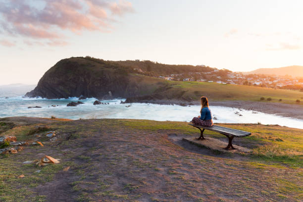 Woman Watches the Sun Set From a Wooden Bench stock photo